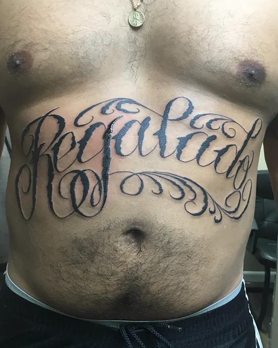 stomach lettering tattoo